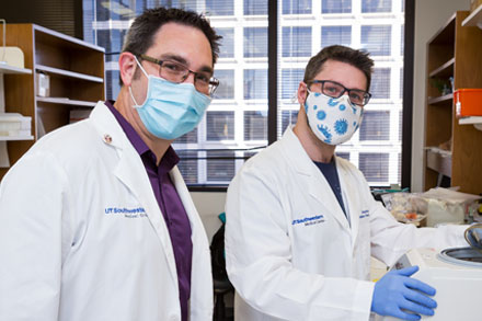 2 male medical professionals wearing surgical masks in lab