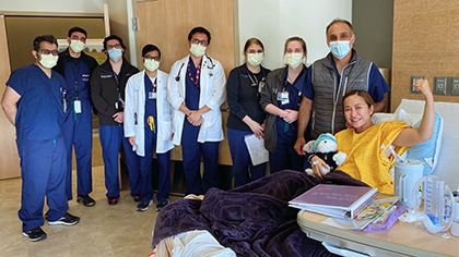 Group of masked healthcare providers around a patient bed. Mom in the bed is holding a stuffed animal.