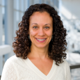 Farra Kahalnik: smiling woman with dark curly hair wearing white sweater