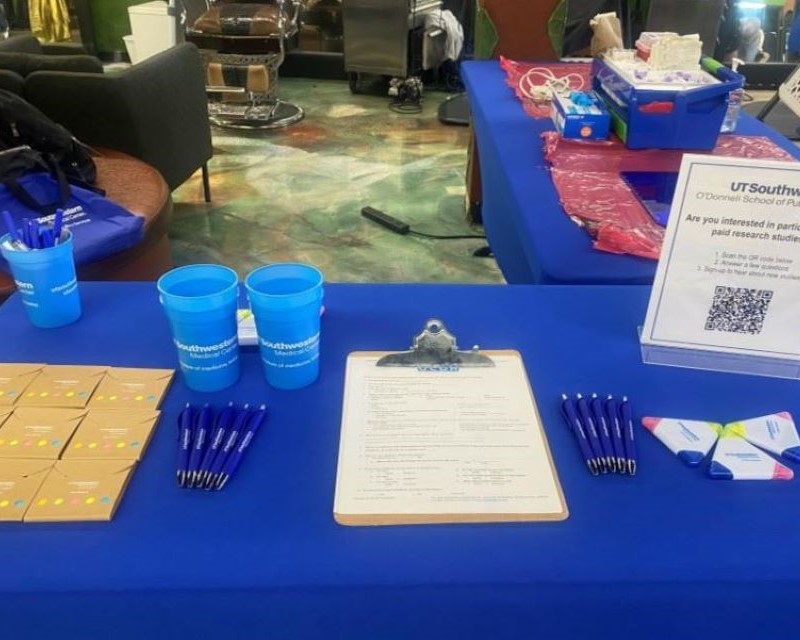 blue tablecloth on event table covered with UTSW swag: pens, cups, highlighters and more