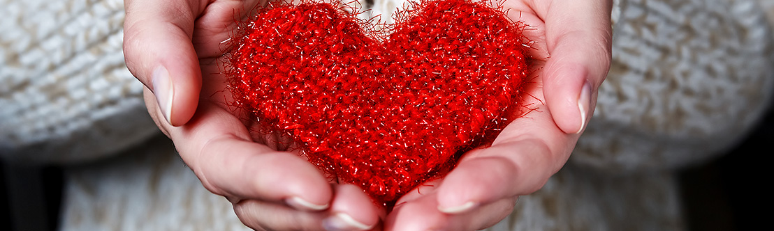hands holding red fabric heart