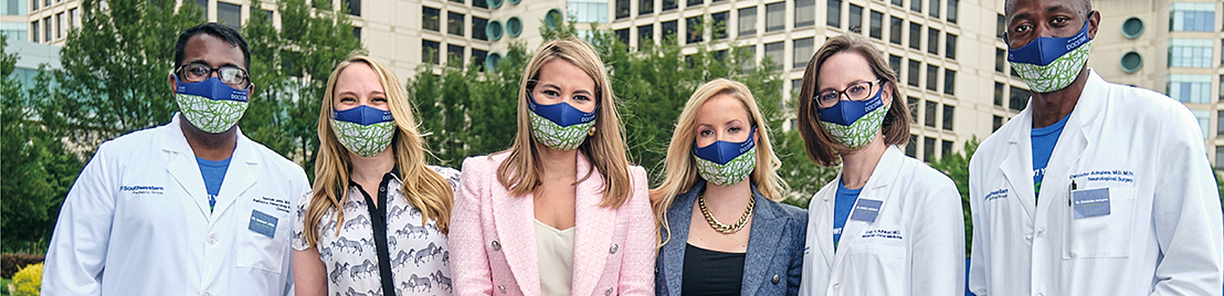 A group of four women and two men wear masks and stand in front of a UT Southwestern building