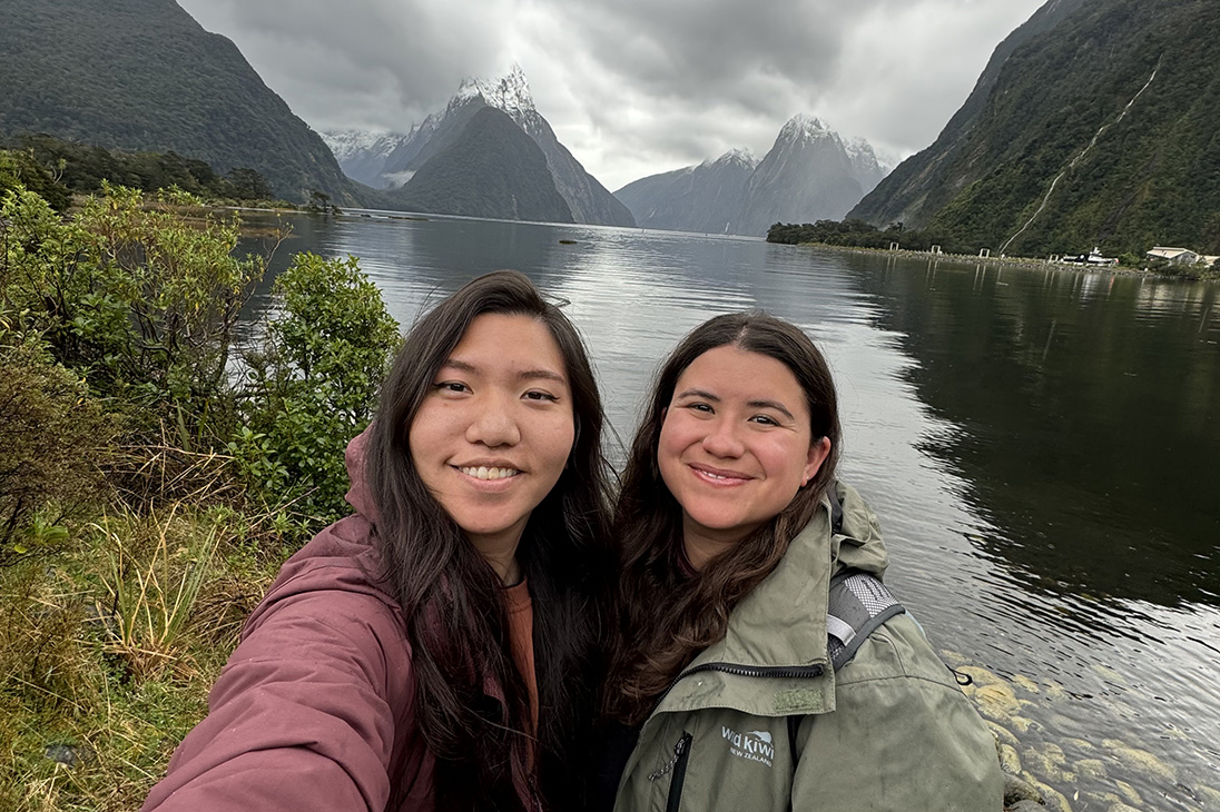 Two women taking a selfie in front of a lake and mountains