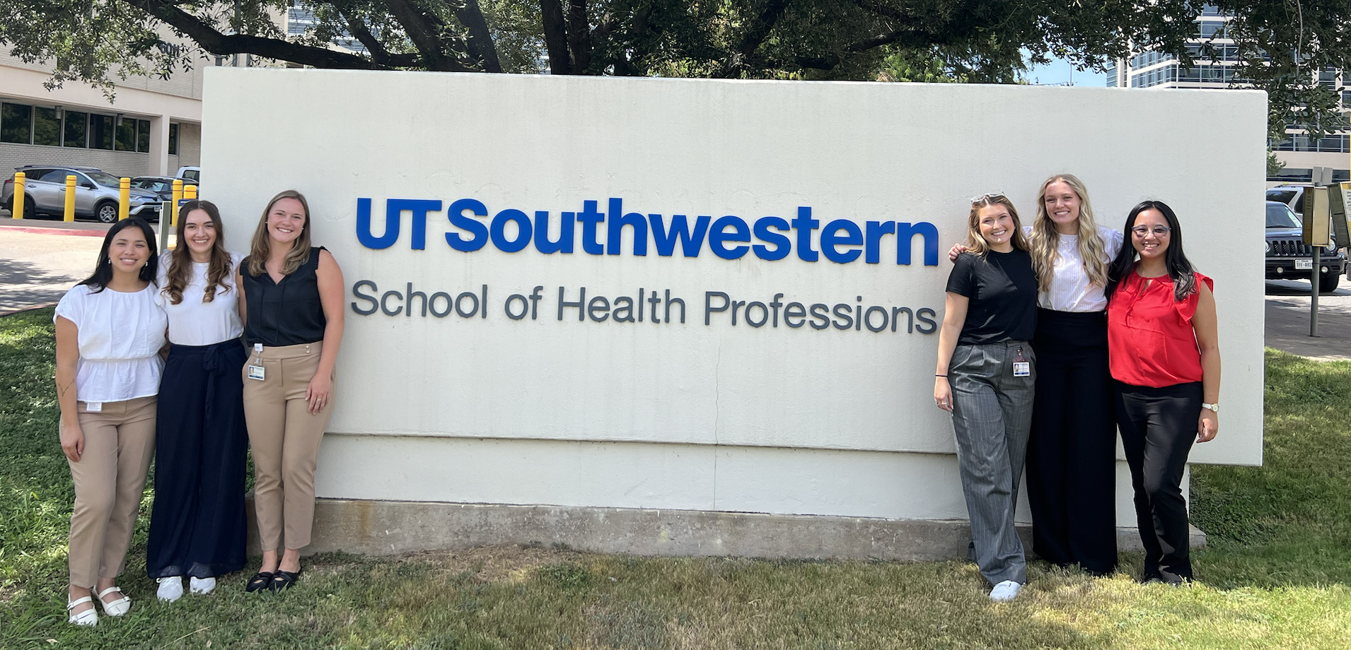 Students standing in front of the School of Health Professions sign