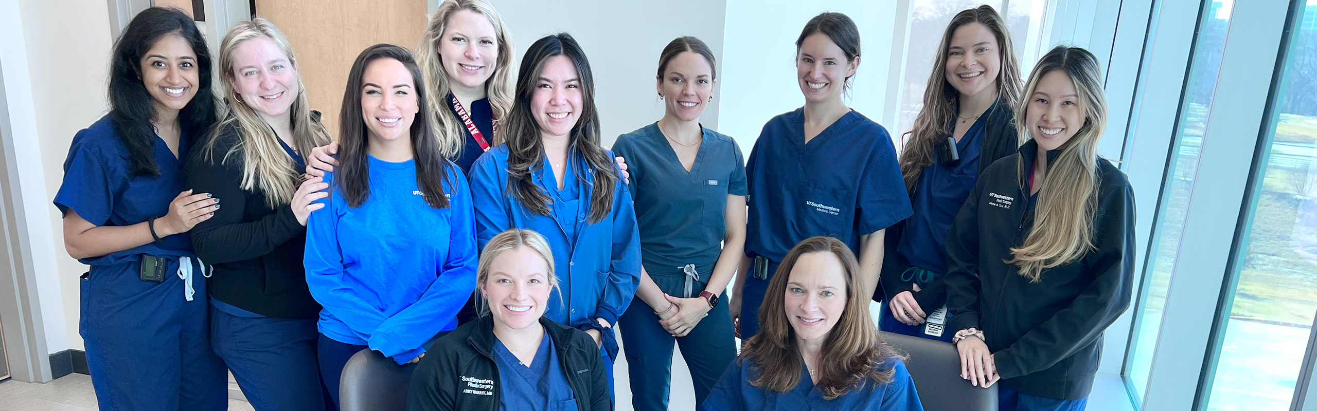 A group of women from the Plastic Surgery Team wearing UT Southwestern Medical Center uniforms, scrubs and jackets.