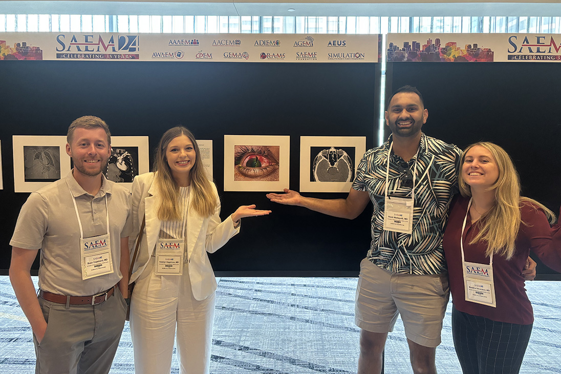 Four residents posing in front of clinical images