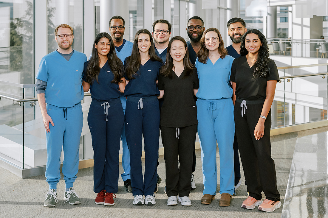 a line of 10 doctors in blue scrubs standing in the CUH lobby
