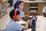 Two young students use laptops during an interactive study session.