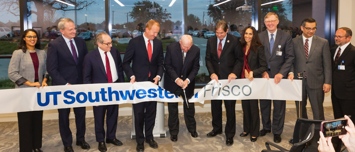 Group of ten people holding a large ribbon that says UT Southwestern Frisco, while person in the middle cuts it with scissors