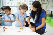 Teacher Ana Moya works on a project with two students building a bed for Goldilocks.