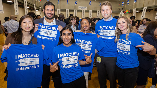 Six smiling students hold up blue t-shirts with their match information printed on it. Copy - I Matched into Internal Medicine at UTMB #utswmatch, I Matched into Med-Peds at UTSW #utswmatch, I Matched into OB/GYN at UW #utswmatch, I Matched into Internal Medicine at Jefferson #utswmatch, I Matched into Pediatrics at Phoenix Children's #utswmatch, and I Matched into Psychiatry at Jackson - MS #utswmatch