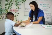 Ms. Moya and a student complete a coloring activity.