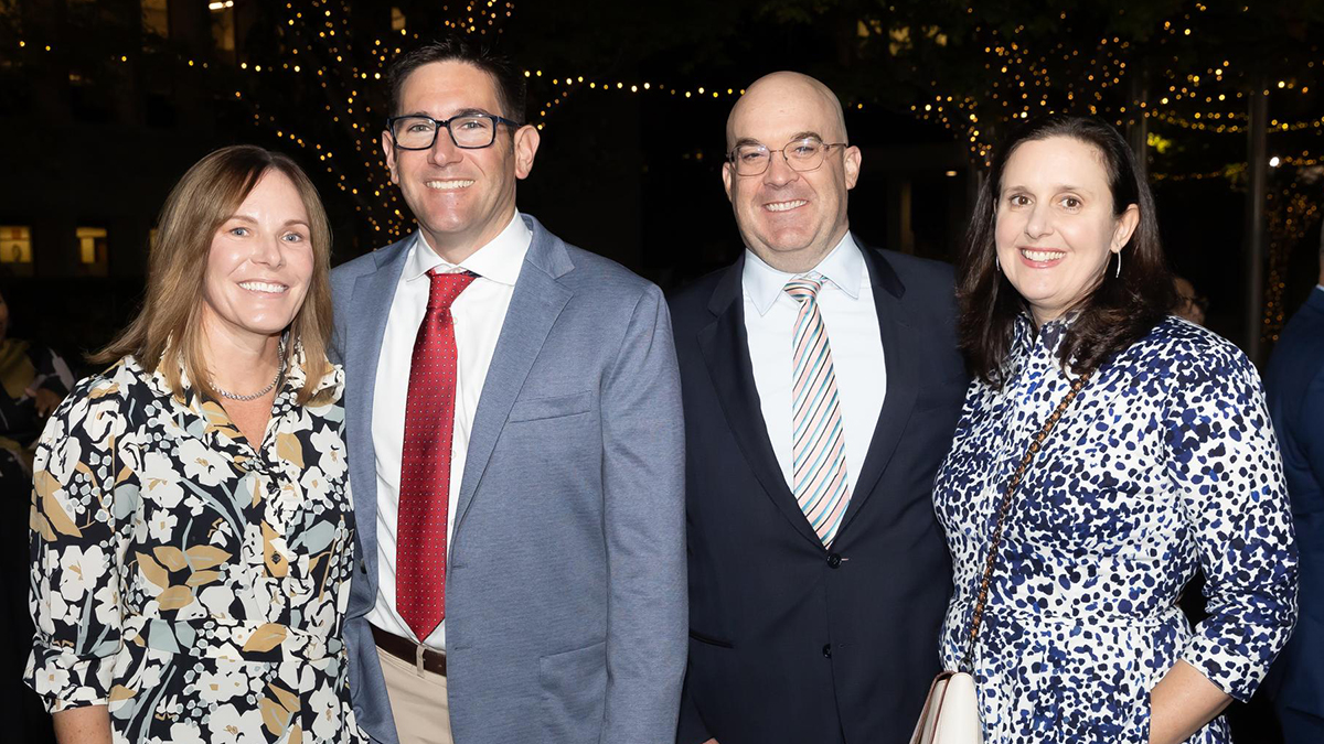 Two smiling couples, posing together.