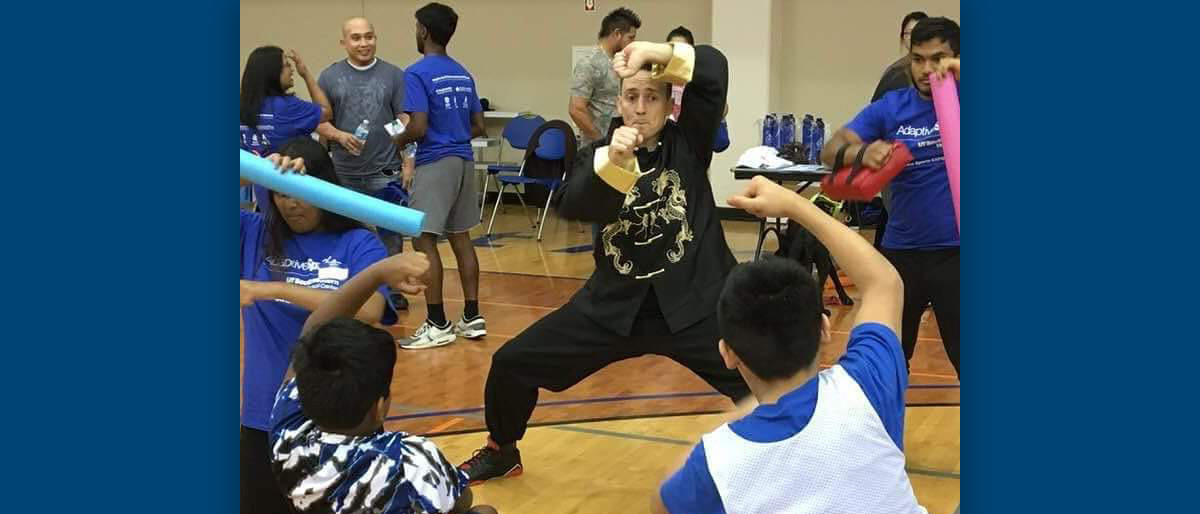 Man in black outfit showing students a fighting stance