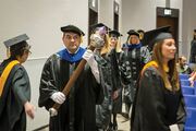 Dr. Gilberto Moralez Jr., Assistant Professor in the School of Health Professions, carries the Vernie A. Stembridge, M.D., Academic Mace as he leads graduates in the procession.