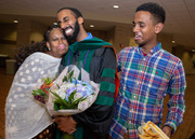 A family squeezes their graduate close after surprising him with flowers.