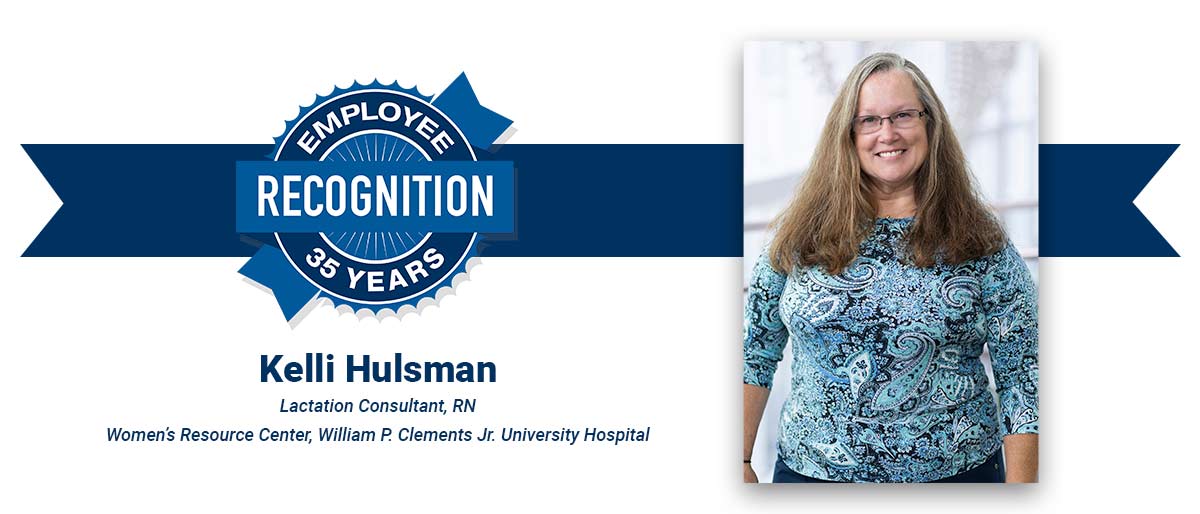 Smiling woman with long highlighted hair, wearing a blue print blouse and dark-rimmed glasses, on white banner with-Kelli Hulsman, Lactation Consultant, RN, Women’s Resource Center, William P. Clements Jr. University Hospital, and blue Employee Recognition Program logo.