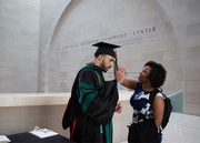 Dr. Evan Wright gets help with regalia from Adrienne Walker.