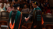 Angela Mihalic, M.D., Dean of Medical Students and Associate Dean of Student Affairs (left), congratulates Bhargav Arimilli, M.D., as he walks the stage to receive his diploma.