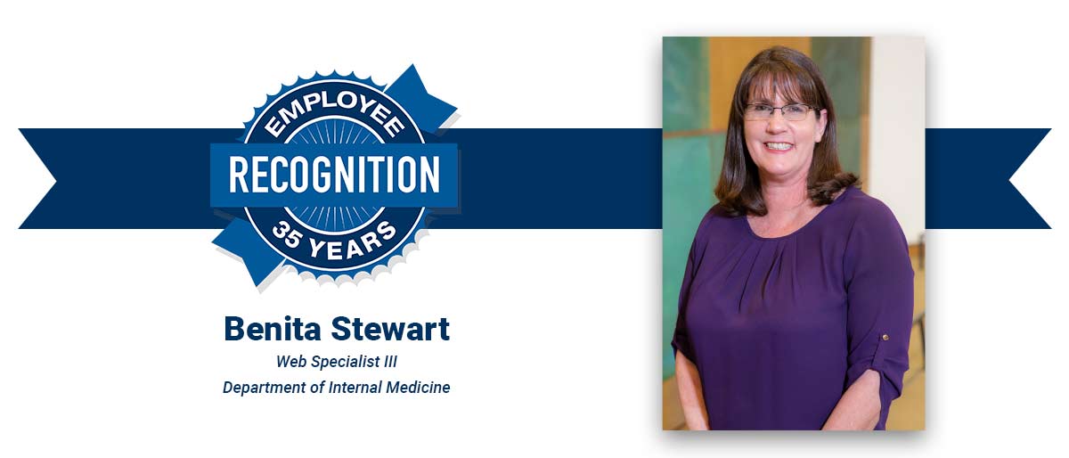 Smiling woman with shoulder-length brown hair and bangs, wearing a purple blouse and dark-rimmed glasses. On white banner with-Benita Stewart, Web Specialist III, Department of Internal Medicine, with blue Employee Recognition Program logo.