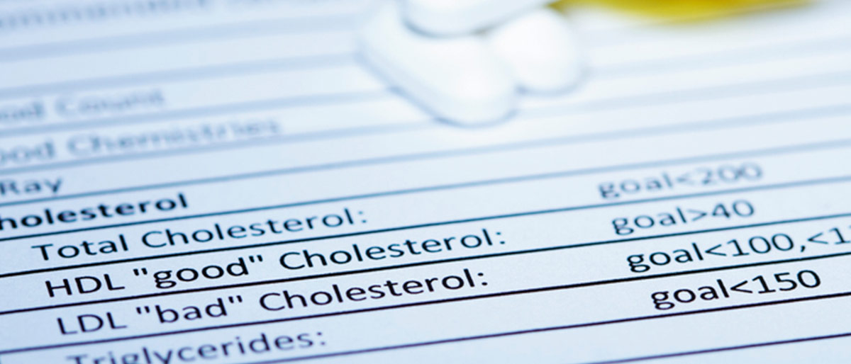 Bottle of pills on sheet showing cholesterol levels