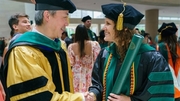 Linnan Tang, M.D., Ph.D., shakes hands with graduate Ashlyn Lafferty, M.D., M.P.H.