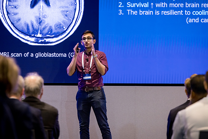 Man on stage in front of screen, speaking to an audience.