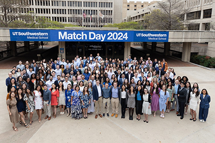 All the matched students gathered outside in front of a banner. Banner copy: UT Southwestern Medical School - Match Day 2024 - UT Southwestern Medical School