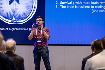 Man on stage in front of screen, speaking to an audience.