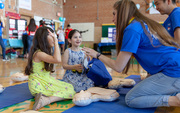 Two young students learn about chest compressions at the CPR station.