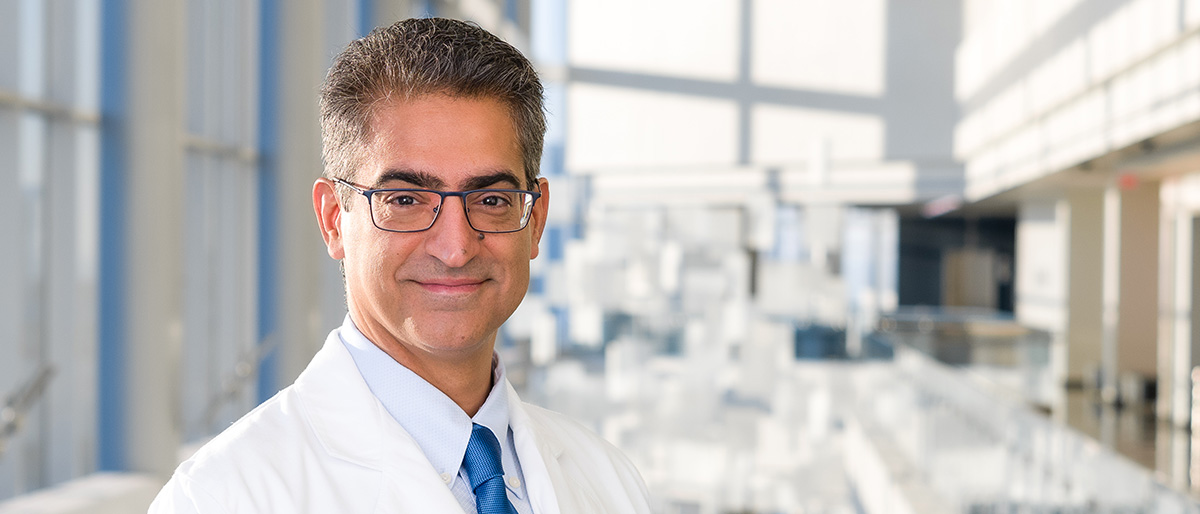 Smiling man with salt-n-pepper hair, wearing a white UT Southwestern Medical Center lab coat, and glasses.