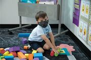 A student works with colored foam blocks to express his creativity and learn his shapes.