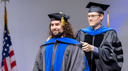 Manolo Rios, Ph.D., M.S., is hooded by his mentor, Jeffrey Woodruff, Ph.D., Assistant Professor of Cell Biology and Biophysics.