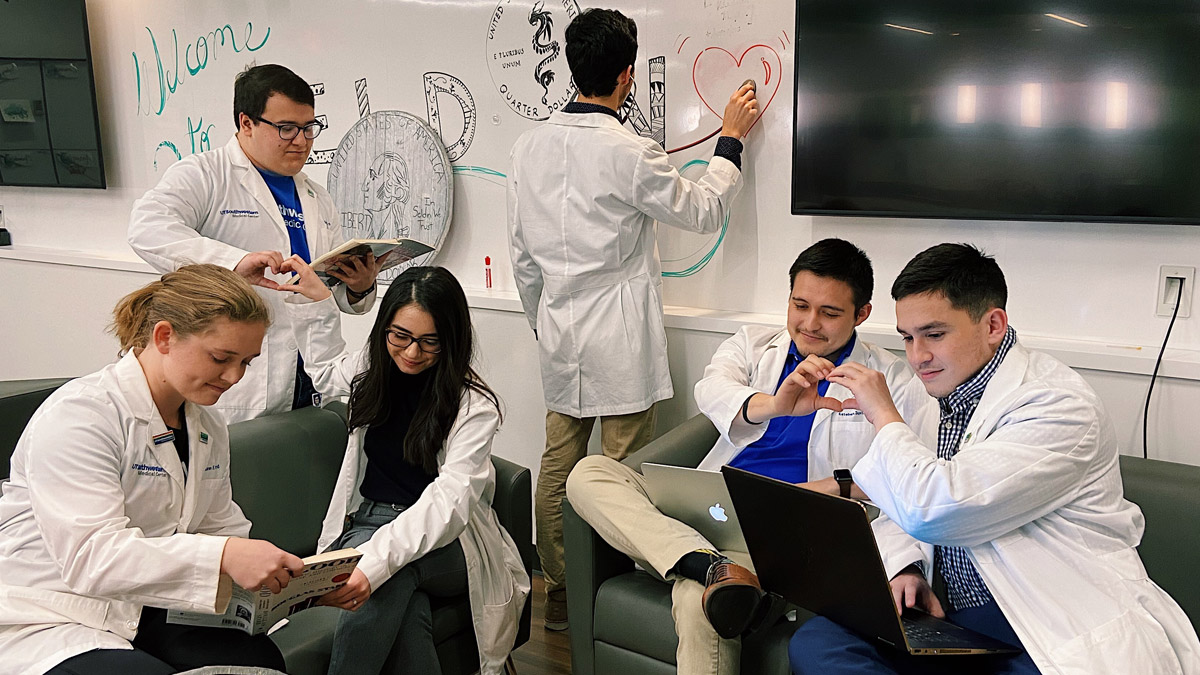 Group of young people in lab coats making heart shapes with their hands