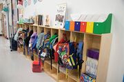 Students’ backpacks are neatly lined up along a wall. Messages are found on classroom walls promoting science and innovation.