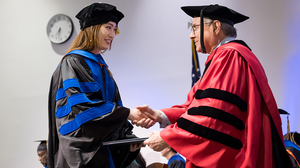 Yin Gao, Ph.D., M.S., receives her degree from Daniel K. Podolsky, M.D., President of UT Southwestern. She was one of more than 80 students to complete her education at UT Southwestern's Graduate School of Biomedical Sciences on May 17.