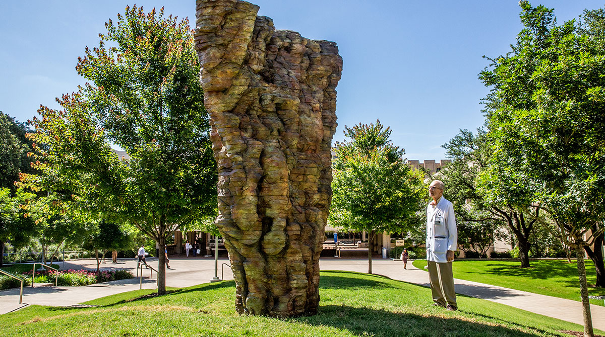 Dr. Cox gazing up at sculpture from grassy hill