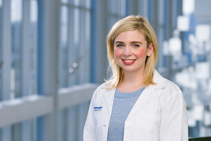 Smiling woman with blond hair wearing a white lab coat.