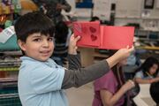 A student shows off the final product of his card, filled with hearts.