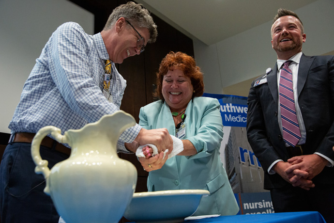 Associate Chief Nursing Officer Victoria England (center) receives the traditional “Blessing of the Hands” from the Rev. John O’Neal, Director of Spiritual Care and Support.