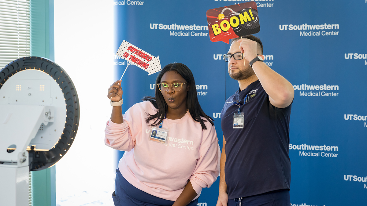 Two employees pose for a picture with silly signs.