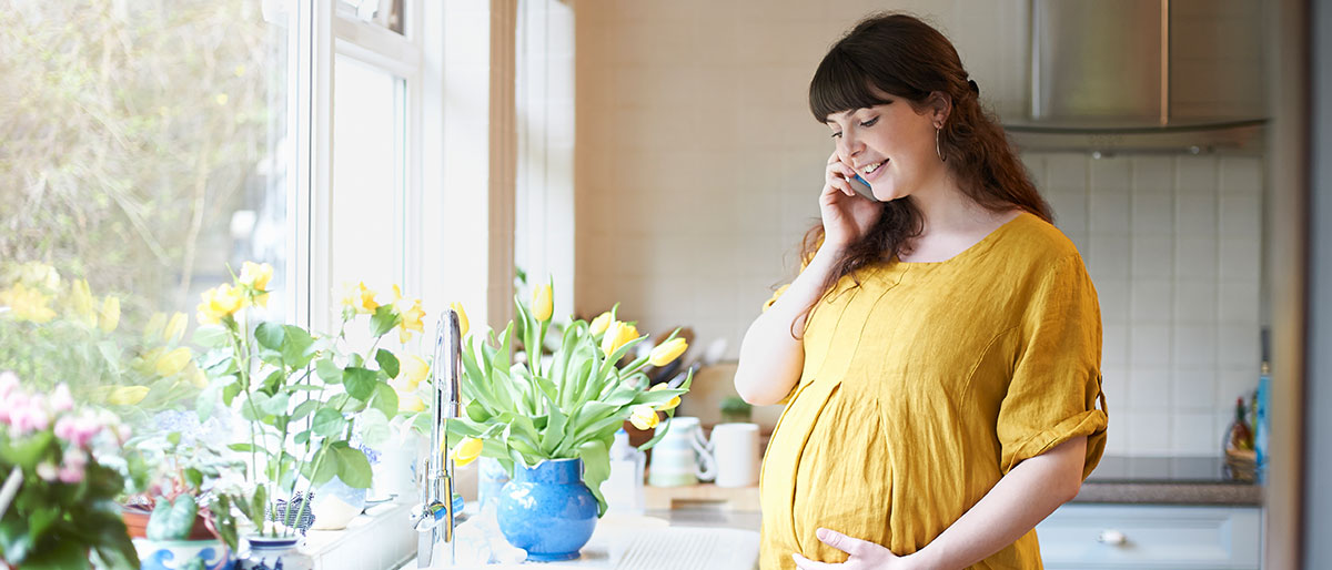 Pregnant woman in yellow dress on phone