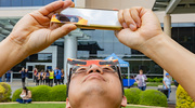 Yonggang Zheng, Ph.D., Assistant Professor of Physiology, takes a photo, shielding his phone's camera lens with eclipse glasses.