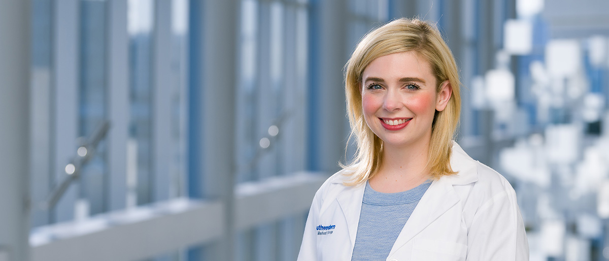 Smiling woman with blond hair wearing a white lab coat.