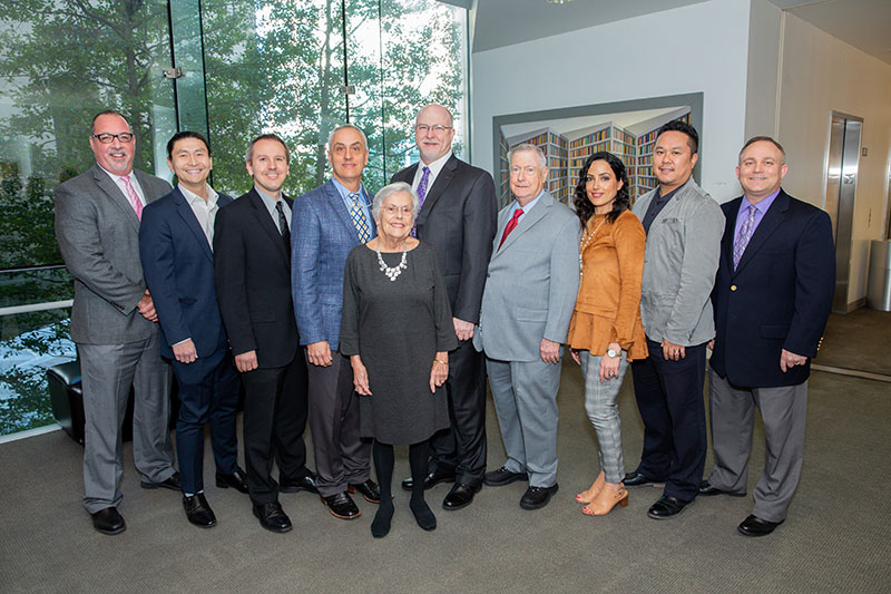 Dr. Patricia Capra (front) and her son, Dr. Jay Capra, pose for a group photo with event presenters and administrators from the School of Health Professions. Back (l-r): Dr. Jon Williamson, Dean; Dr. Mu Huang; Dr. Jason Zafereo; Dr. Jay Capra; Dr. Ross Querry; Dr. Gordon Green, former Dean; Dr. Hoda Yeganehjoo; Dr. Masaki Mizuno; and Dr. Scott Smith, Assistant Dean for Research.