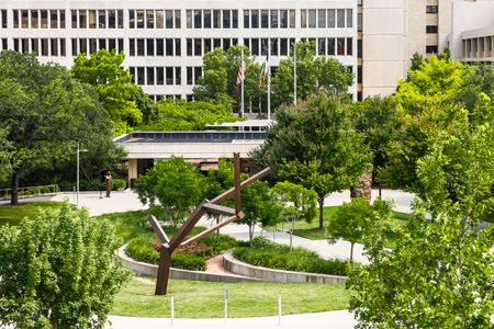 Overhead view of metal sculpture and garden in front of large building.