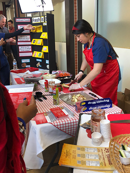 Womanin red apron standing behind a table working with food