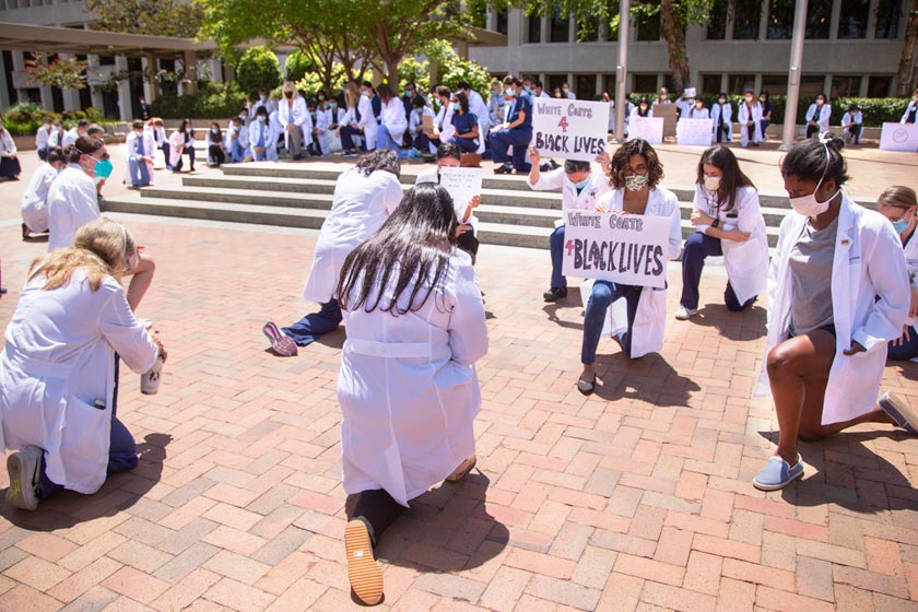Crowd of people in white lab coats kneeling