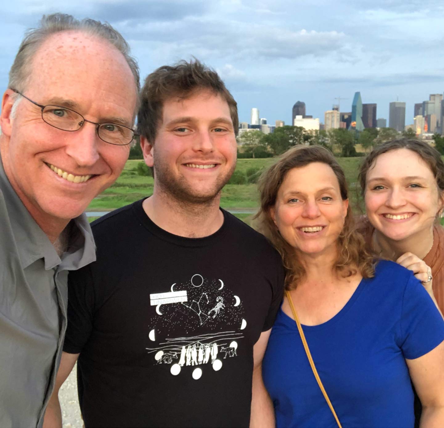 Four people standing in front of Dallas skyline