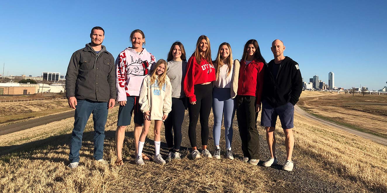 Eight people standing in field in front of city skyline